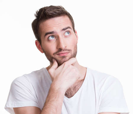 Portrait of the young thinking man looks up in casuals isolated on white background.の写真素材