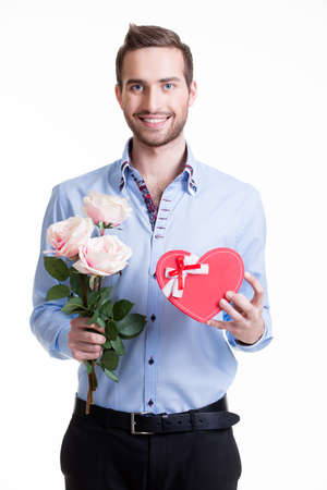 Young happy man with a pink roses and a gift - isolated on white.の写真素材