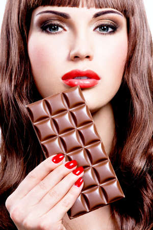 Portrait of beautiful sexy woman with bar of chocolate. Closeup face with bright makeup, isolated on white.の写真素材