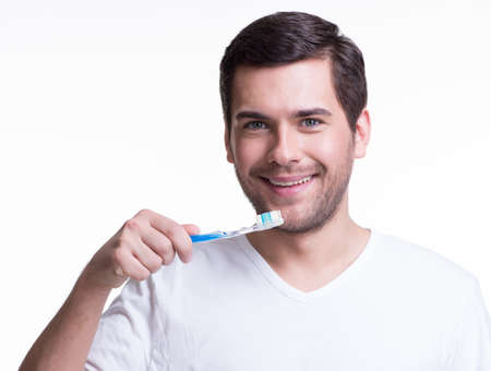 Portrait of a smiling young man with a toothbrush in a white t-shirt -  isolated on white.