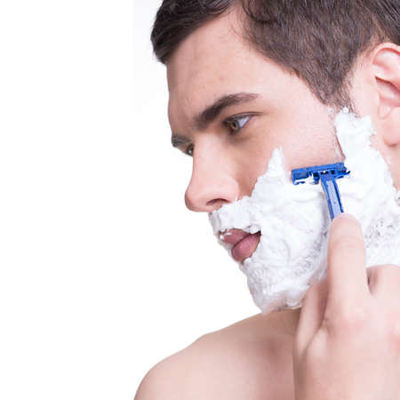 young man shaving the  beard with the razor - isolated on whiteの写真素材