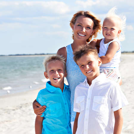 Portrait of smiling mother with children standing on the sunny beach.
