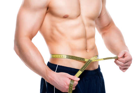 Young handsome man with a muscular torso uses measuring tape - isolated on white background.