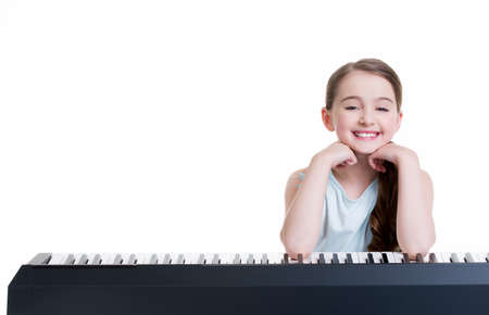 Cute happy smiling girl plays on the electric piano - isolated on white.の写真素材