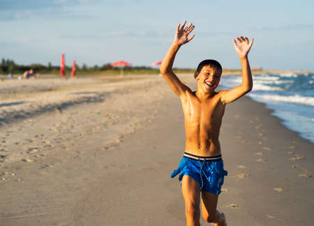 Happy boy running on the sea beach at summer.の写真素材