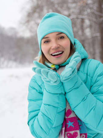 Portrait of young happy woman in blue jacket at the winter park.