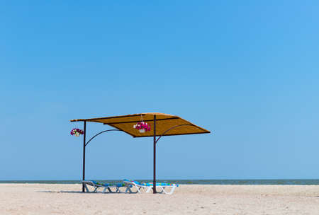 Sunbeds with thatched canopy at the empty beach. Vacation and tourism concept.の写真素材