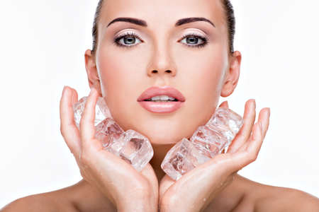 Beautiful young woman applies the ice to face. Skin care concept.の写真素材