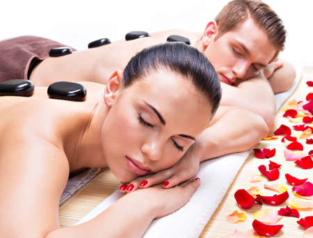Portrait of attractive couple relaxing in spa salon with hot stones on body.の写真素材