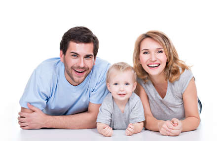 Photo of the smiling young parents with little child lying on the floor - isolated on white background.の写真素材