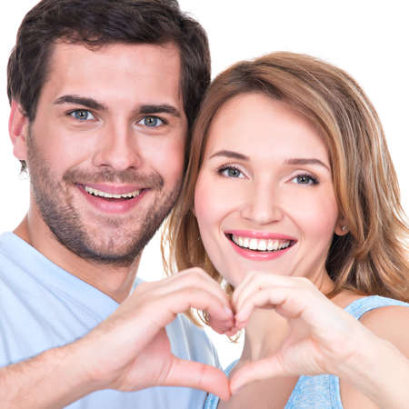 Closeup portrait of of cheerful smiling couple standing together show hands heart -  isolated on...