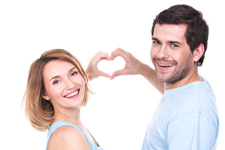 Portrait of cheerful smiling couple standing together show hands heart -  isolated on white...