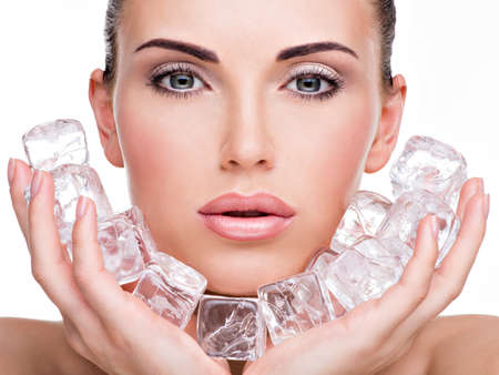 Beautiful young woman applies the ice to face. Skin care concept.の写真素材