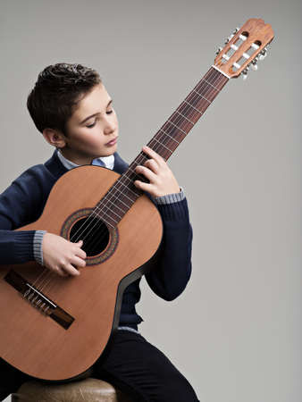 Caucasian  boy playing on acoustic guitar. Teenager boy with classic wooden guitarの写真素材