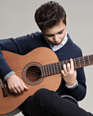 Caucasian  boy playing on acoustic guitar. Teenager boy with classic wooden guitarの写真素材