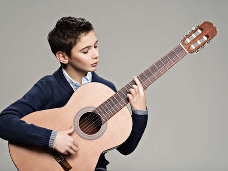 Caucasian  boy playing on acoustic guitar. Teenager boy with classic wooden guitarの写真素材