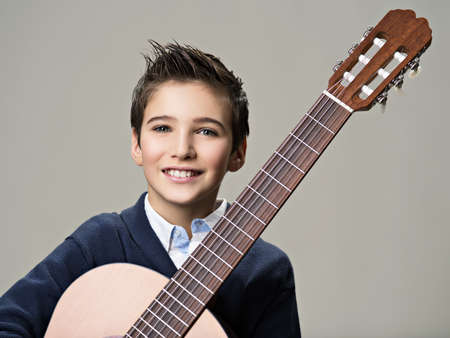 Smiling boy with guitar. Teenager boy with classic wooden acoustic  guitarの写真素材