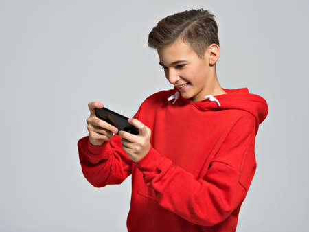 Amused teenager playing games on smartphone   - posing at studio
の写真素材