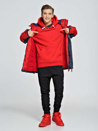 Teenage boy dressed in a sport wear. Teenager wears fashionable fall clothes - posing over white...
