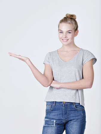 Portrait of a beautiful adult happy woman with presentation gesture over white backgroundの写真素材