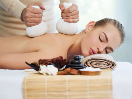 Young woman getting masaage with hot stones in spa salon.  The girl's relaxing on spa procedures. Beauty treatment concept.の写真素材