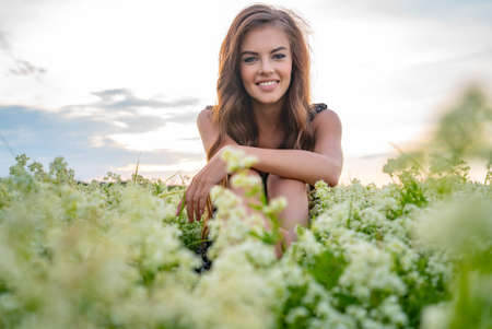 Young cheerful woman sitting in a field of white lavender flowersの写真素材