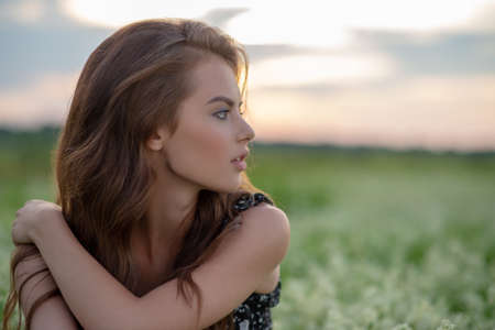 Profile portrait of an Young woman sitting in a field of white lavender flowersの写真素材