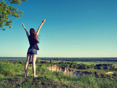 Peaceful girl standing by a cliff enjoying the landscapeの写真素材