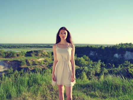 Young woman standing by a cliff with a nice view behind he backの写真素材