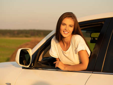 Happy smiling woman in the car looking out of window. Beautiful caucasian girl in the car on the...