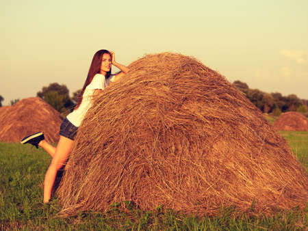 Beautiful young woman is relaxing on the haystackの写真素材