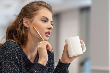 Ideas for business. Studying and working at home. Thoughtful young woman making notes using notepad...