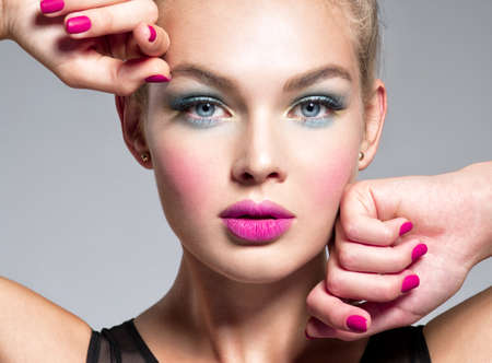 Beautiful woman face with blue makeup of eyes and pink nails. Glamour fashion model.  Fashion portrait of a attractive woman with bright makeup.  Gorgeous girl.の写真素材