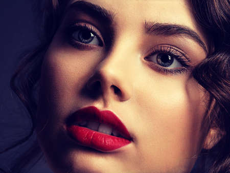 Closeup Face of a beautiful woman with a smoky eye makeup and red lipstick. Sexy and gorgeous brunette girl. Portrait of an attractive female -  at studio. Fashion model.の写真素材
