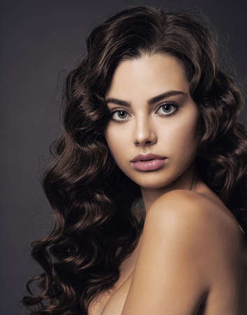 Beautiful young woman with long curly brown hair and  smoky eye makeup. Sexy and gorgeous brunette...