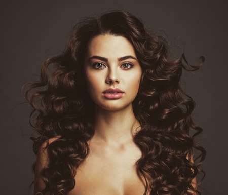 Beautiful young woman with long curly brown hair and  smoky eye makeup. Sexy and gorgeous brunette...