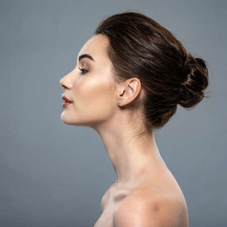 Beautiful woman cares for the skin neck- posing at studio isolated on white. Beautiful face of  a caucasian model with clean fresh skin.の写真素材
