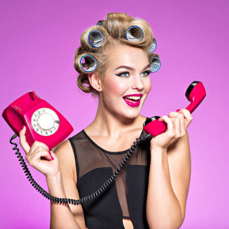 Portrait of a cheerful angry caucasian woman yelling at retro telephone.の写真素材