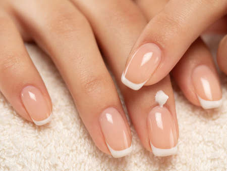 Woman applies a cosmetic moisturizer on her hands. Beautiful female hands. Woman gets manicure procedure in a spa salon. Hand care. Woman cares for the hands. Beauty treatment with skin of hand.の写真素材