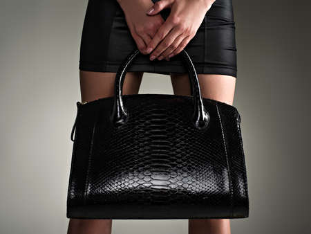 Beautiful woman holds stylish black bag. Fashionable girl. Glamour stylish concept. Art. Woman after shopping. Unrecognizable female.の写真素材