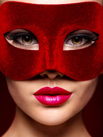 Woman in red  theatre mask on face with violet lipsの写真素材