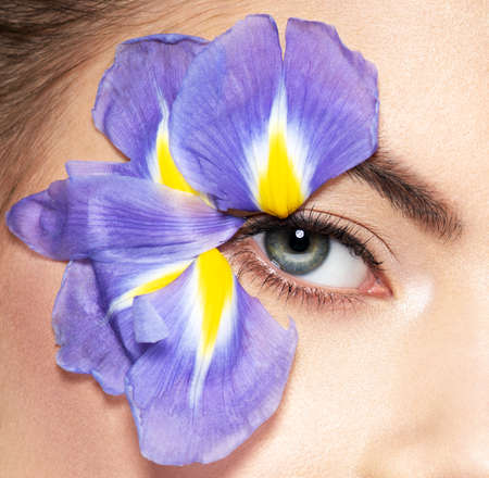 portrait of young beautiful woman with Fashion makeup of eyes. Pretty adult girl with blue flowers near the face, isolated on white. Skin care. Beauty treatment.の写真素材