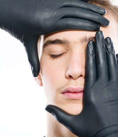 Face skin check. Beautician touching male face. Doctor checks a skin. Beauty treatments. Plastic surgery doctor is touching face of  young manの写真素材