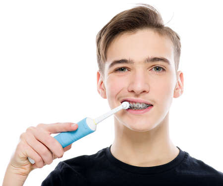 Teenager brushes his teeth with a toothbrush. Photo of  young man taking care of his teeth. Dental hygiene.  Caucasian guy takes care of clean teeth with braces.  Person with healthy teeth.の写真素材