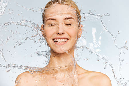 Photo of  young  woman with clean skin and splash of water. Portrait of smiling woman with drops of...