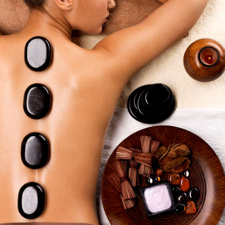 Portrait of young woman getting hot stone massage in spa salon. Beauty treatment concept.の写真素材
