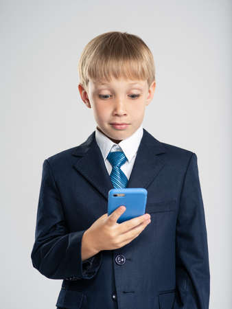 Photo of a shocked businessman  boy with smartphone.  Portrait of a excited  kid in a blue business...