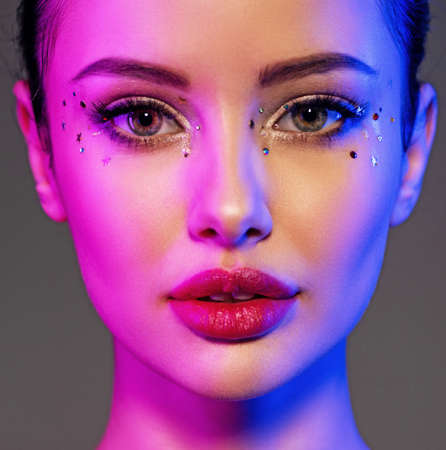 Portrait of the girl is highlighted in bright blue and purple light. Face of a beautiful model....