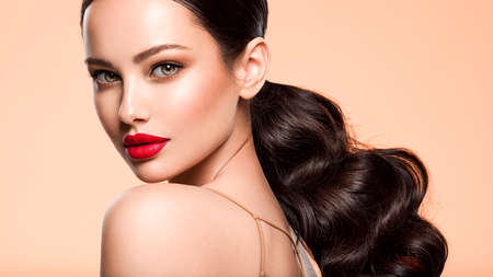 Beautiful white girl with a red lipstick on lips. Stunning brunette girl with long hair tail. ...