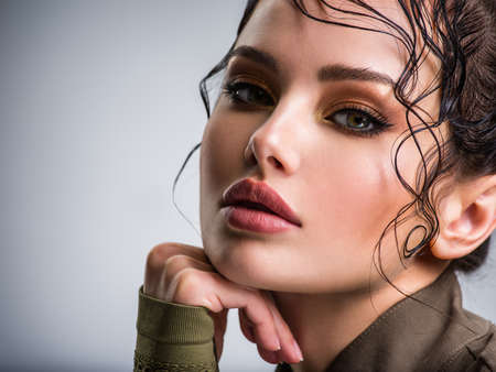 Closeup portrait of a beautiful young fashion woman with brown makeup posing at studio. Beautiful  woman Face with a bang. Model looking at camera.の写真素材
